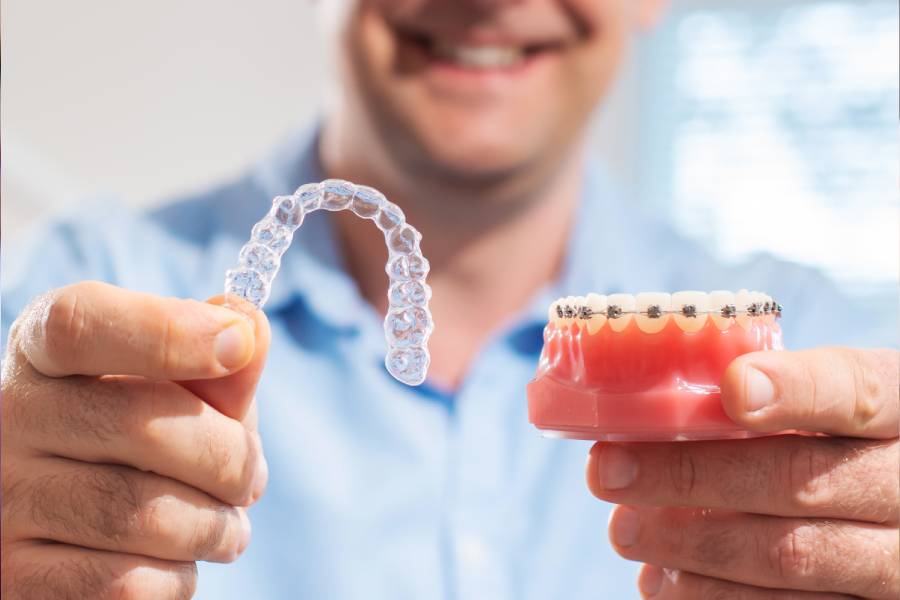 Man holding Traditional braces and Invisalign indicative for comparing